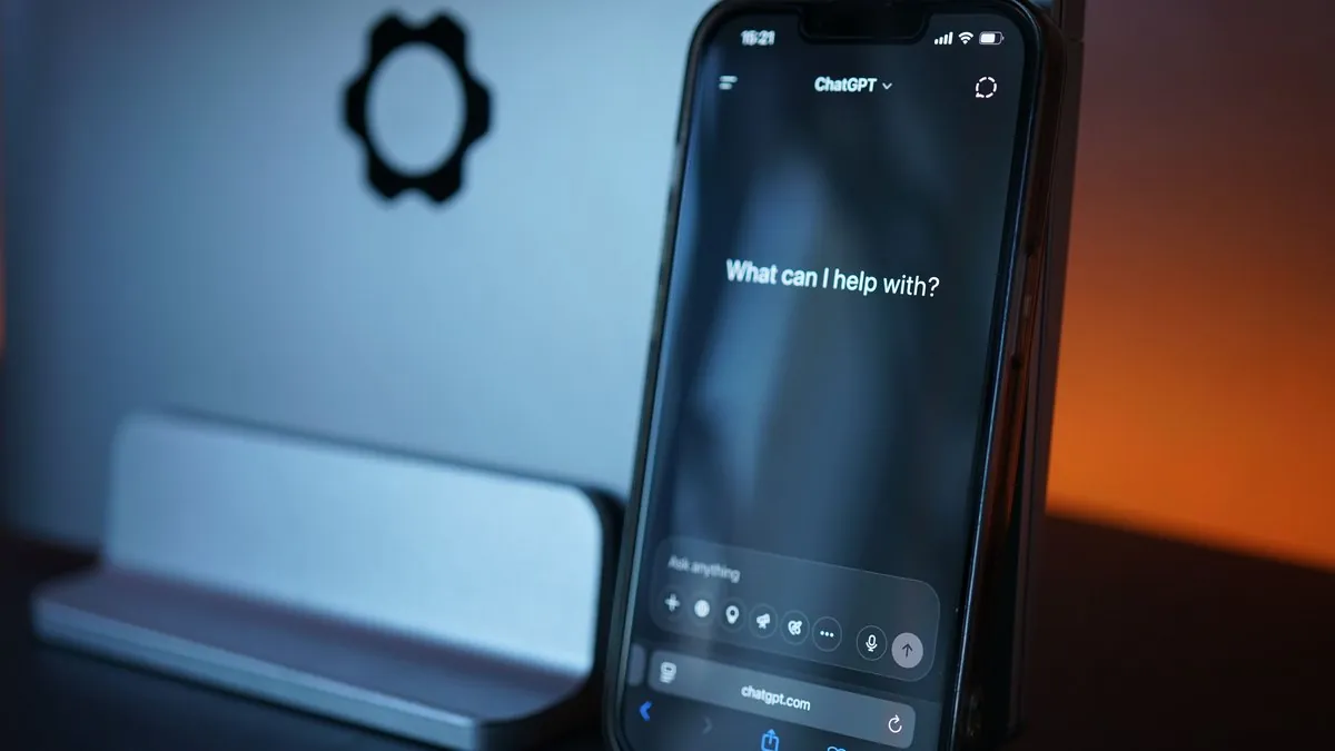 Kundenservice automatisieren: Smartphone mit geöffnetem ChatGPT-Chatfenster vor einem Monitor auf einem Schreibtisch