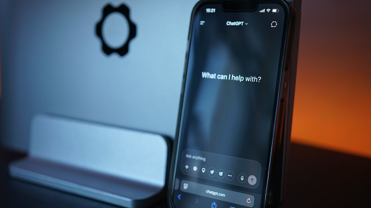 Kundenservice automatisieren: Smartphone mit geöffnetem ChatGPT-Chatfenster vor einem Monitor auf einem Schreibtisch